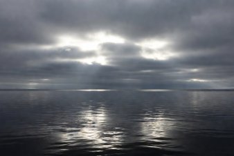 Overcast sky showing bright luminous white patches contrasting with dark open-water reflections