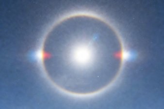 A brilliant sun surrounded by a circular 22 degree halo with bright mock suns on either side