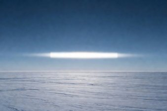 A flattened, distorted rectangular sun hovering above a frozen horizon line